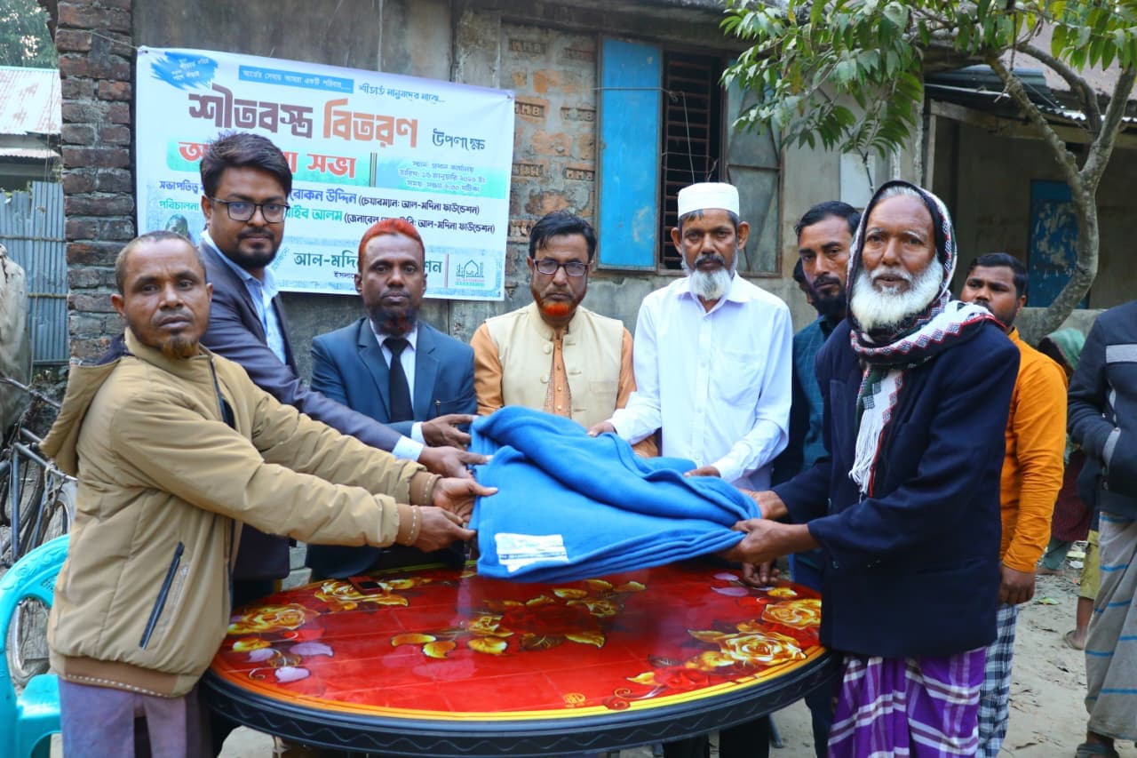 মাথায় মাফলার জড়ানো একজন প্রবীণ নীল কম্বল গ্রহণ করছেন।